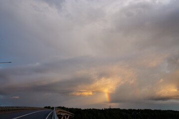 Dramatic cloudscape with puffy clouds lit by orange setting sun and blue sky.