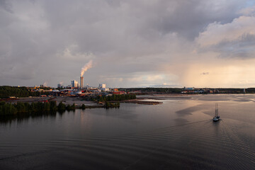 Industrial landscape with lake, stormy sky and factory during golden hour. Industry harmonized with nature concept