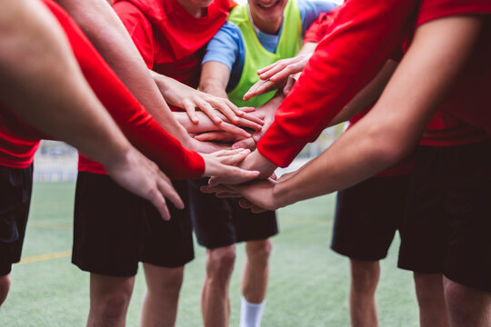 Soccer team stacking hands together on field