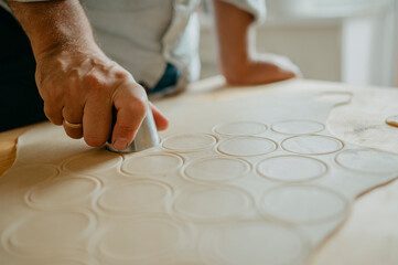 Hand of man making circular shapes of dough at home