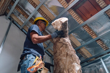 Construction worker working with insulation in attic
