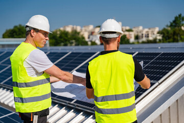 Two technicians strategizing on the rooftop of a corporate building equipped with solar panels