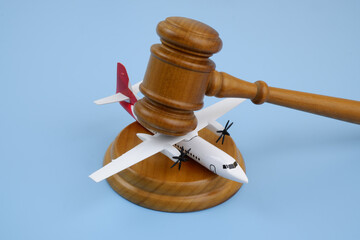 Wooden judge gavel and airplane model on blue background.