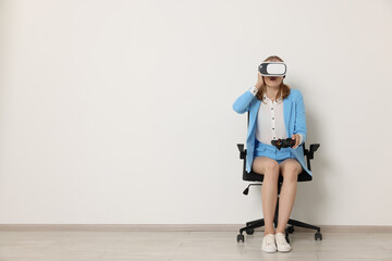 Emotional woman with virtual reality headset sitting on chair indoors, space for text
