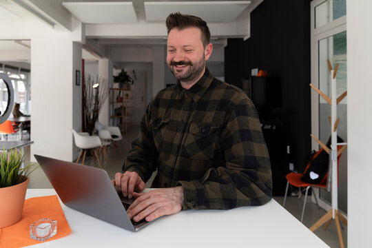 Smiling businessman using laptop at office
