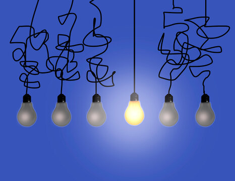Illuminated electric bulb amongst dim bulbs against blue background