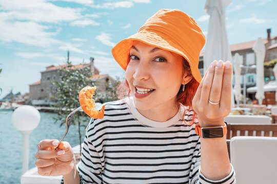 A woman savoring a delicious shrimp dish with an Italian touch, expressing delight with a belissimo gesture.