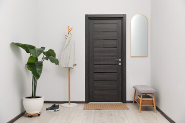 Coat rack, houseplant and shoe storage bench in hallway. Interior design