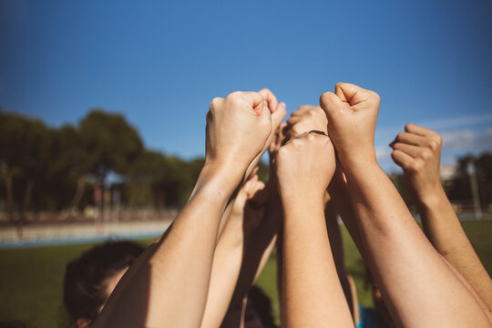 Hands of athletes cheering together on sunny day