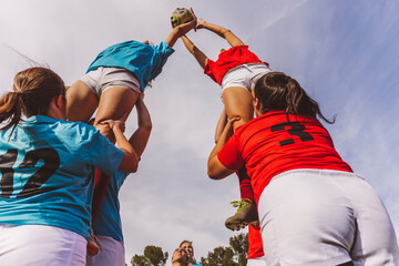 Rugby team holding ball under sky at field