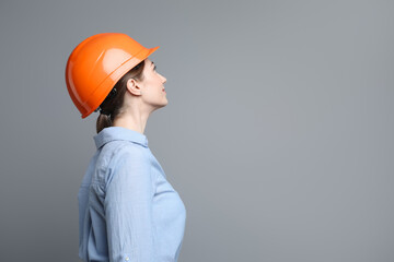 Engineer in hard hat on grey background, space for text