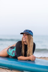 Cheerful woman lying on SUP board on beach