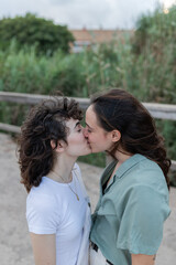 Fototapeta premium Lesbian couple kissing on bridge in daytime