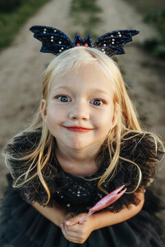 Girl in bat costume making face near field
