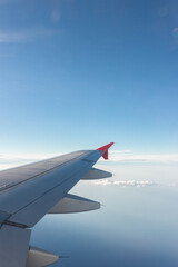 Obraz premium Airplane flying under cloudy sky over ocean and land