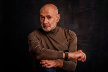 Studio portrait of an elderly man sitting against isolated dark background