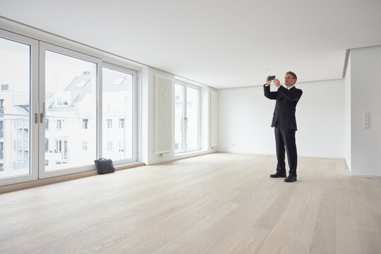 Real estate agent taking pictures through smart phone in apartment