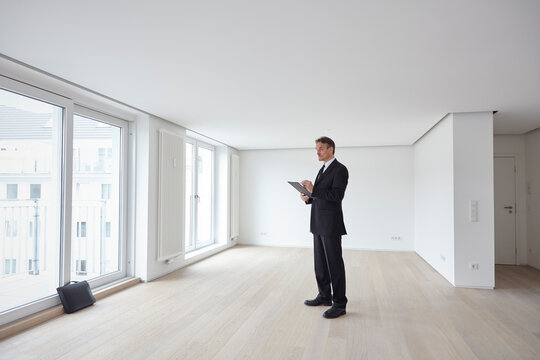 Businessman standing and looking around in empty apartment