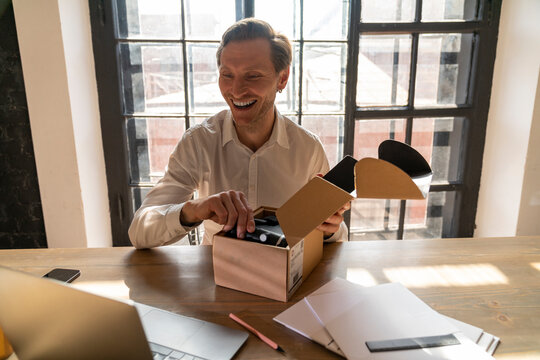 Happy businessman unboxing package at desk