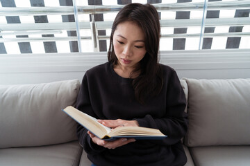 Woman reading a book on a modern patio sofa