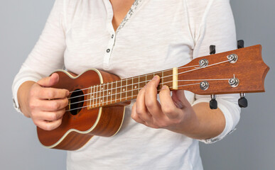 Anonymous close up of hands skillfully playing chords on a ukulele, showcasing the art of music and...
