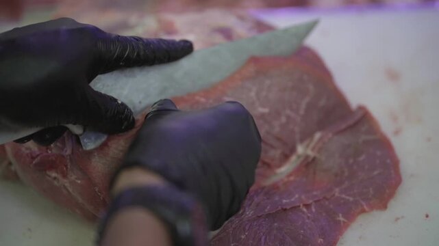Butcher cuts pieces of beef with knife in supermarket. Economic recession. Livestock. Argentina.