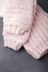 Knitted woolen light pink sweater, folded knit pullover on grey background, close up shot. Copy space