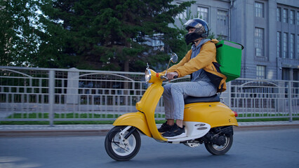 Courier man carry package moped. Guy ride scooter city street deliver box. Green backpack mock up. Fast food delivery service. Person drive bike thermal store bag. Express home order. Rush rider hurry © SERGEI