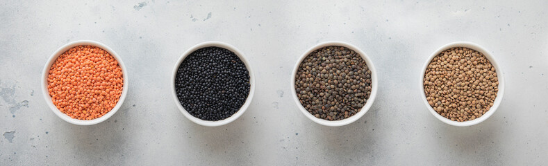 Bowls with various type mixed organic dry lentils seeds on kitchen table.Macro.