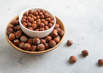 Bowls with peeled and whole healthy hazelnut nuts on light table.Macro.