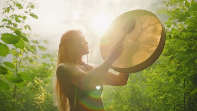 Shamanic woman playing on shaman frame drum, holds leather round musical instrument in hands, plays music beats melody. forest green grass trees fog sun rays light. Fairy Girl musician drummer art 4k