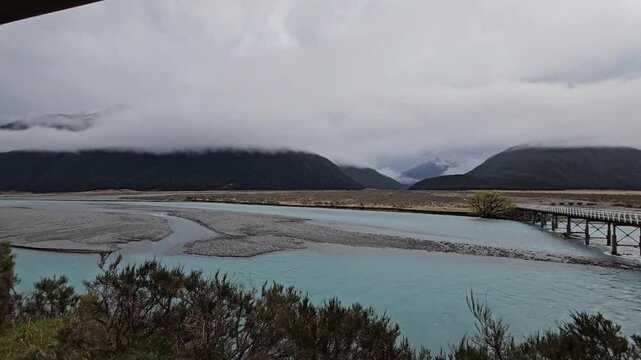 4K, Tranzalpine train journey New Zealand, glacier glacial braided river, mountains clouds and rain, tourist tourism travel journey destination