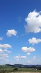 Peaceful Countryside Under Expansive Blue Sky with Serene White Clouds