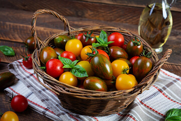 Multi-colored tomatoes in wickerwork basket. Different types of fresh tomatoes