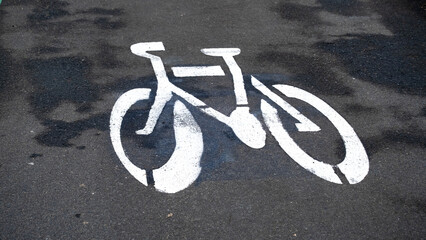 Close up of bicycle symbol painted in white on tarmac bike lane for cyclist