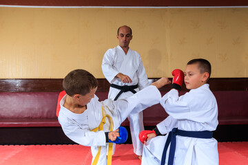 Athlete boy in blue pads throws a roundhouse kick to the head of an athlete in red pads