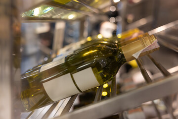 A row of wine bottles on a shelf, one of which is labeled with a white label