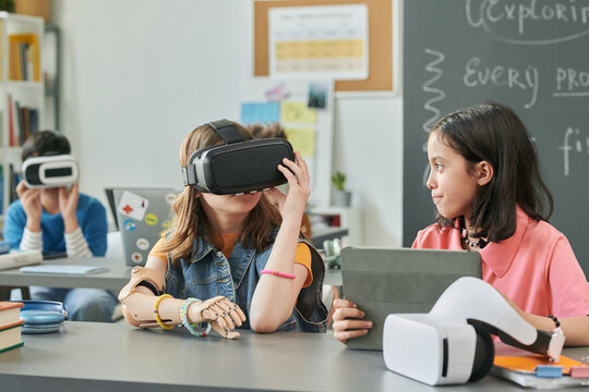 Portrait of two girls using virtual reality technology in school enjoying IT class for children copy space