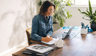 Businesswoman writing notes during online meeting