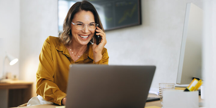 Successful businesswoman excelling in phone call and laptop work in office