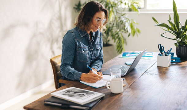 Businesswoman writing notes during online meeting