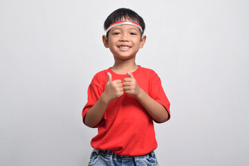 A happy Indonesian boy in red shirt giving thumbs up, isolated on white background. Indonesian Independence Day concept.