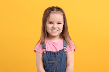 Portrait of happy little girl on orange background