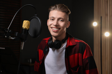 Singer with headphones recording song in professional studio