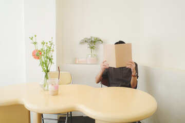 woman covering her face with blank book or magazine in mock up concept.