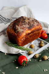 An exquisitely sliced artisan bread loaf is beautifully arranged alongside juicy tomatoes and olives on rustic fabric