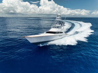Luxury yacht speeding through the ocean under a partly cloudy sky