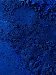 Fototapeta premium A close-up of a rough, dark blue surface with visible cracks. The rough texture of the ground. Powder or a dusty substance.
