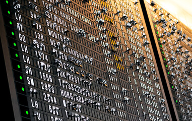 Split flap display at the airport with folding black letter panels showing arrival and departure...