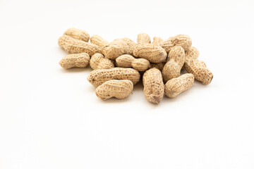 A small pile of peanuts in their shells, scattered on a white surface. A simple and natural snack.